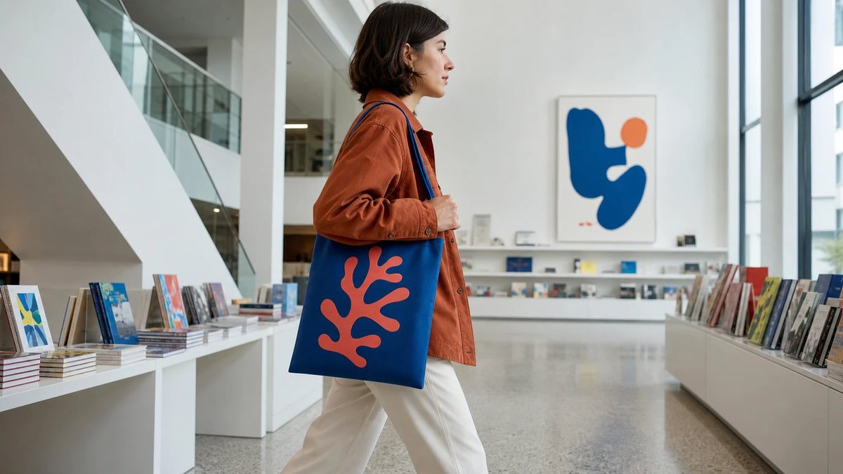 Customer carrying a slim cobalt recycled flat tote in a museum gift shop