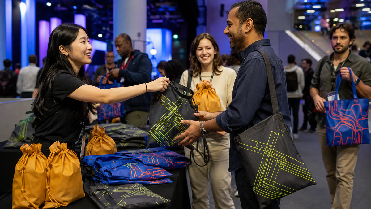 Asistentes a la conferencia llevando bolsas de algodón coordinadas para eventos y bolsas con cordón