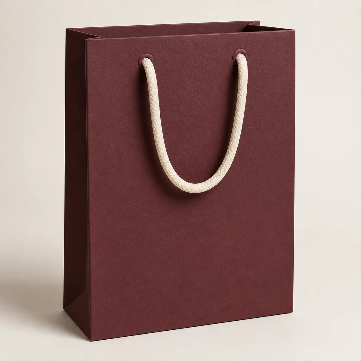 Bolsa de papel boutique de lujo burdeos con asas de cuerda de algodón color crema