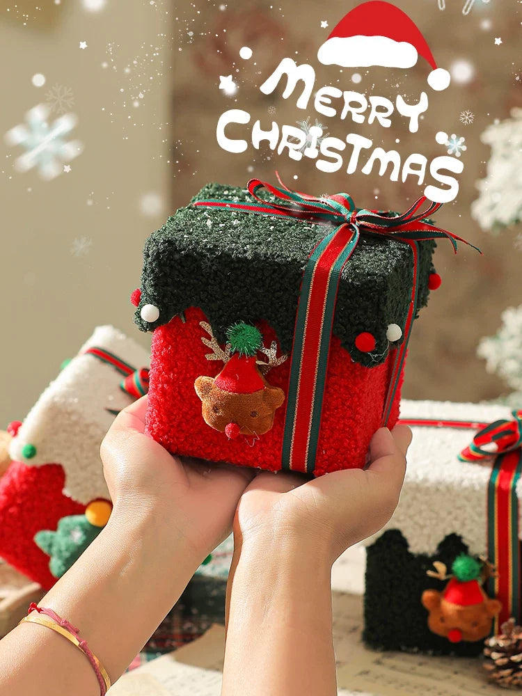 Plush Christmas gift box held in two hands before a multi-item hamper pack-out trial