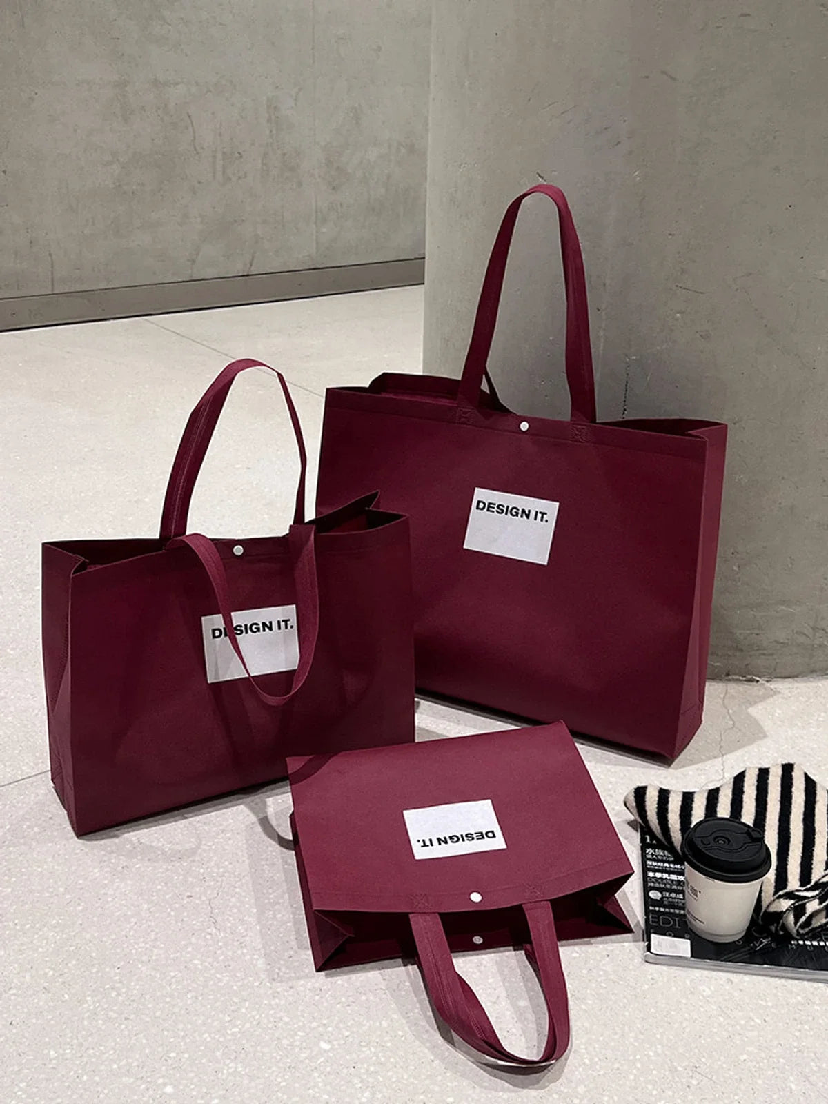 Several red non-woven totes with white rectangular graphics arranged at different visible scales