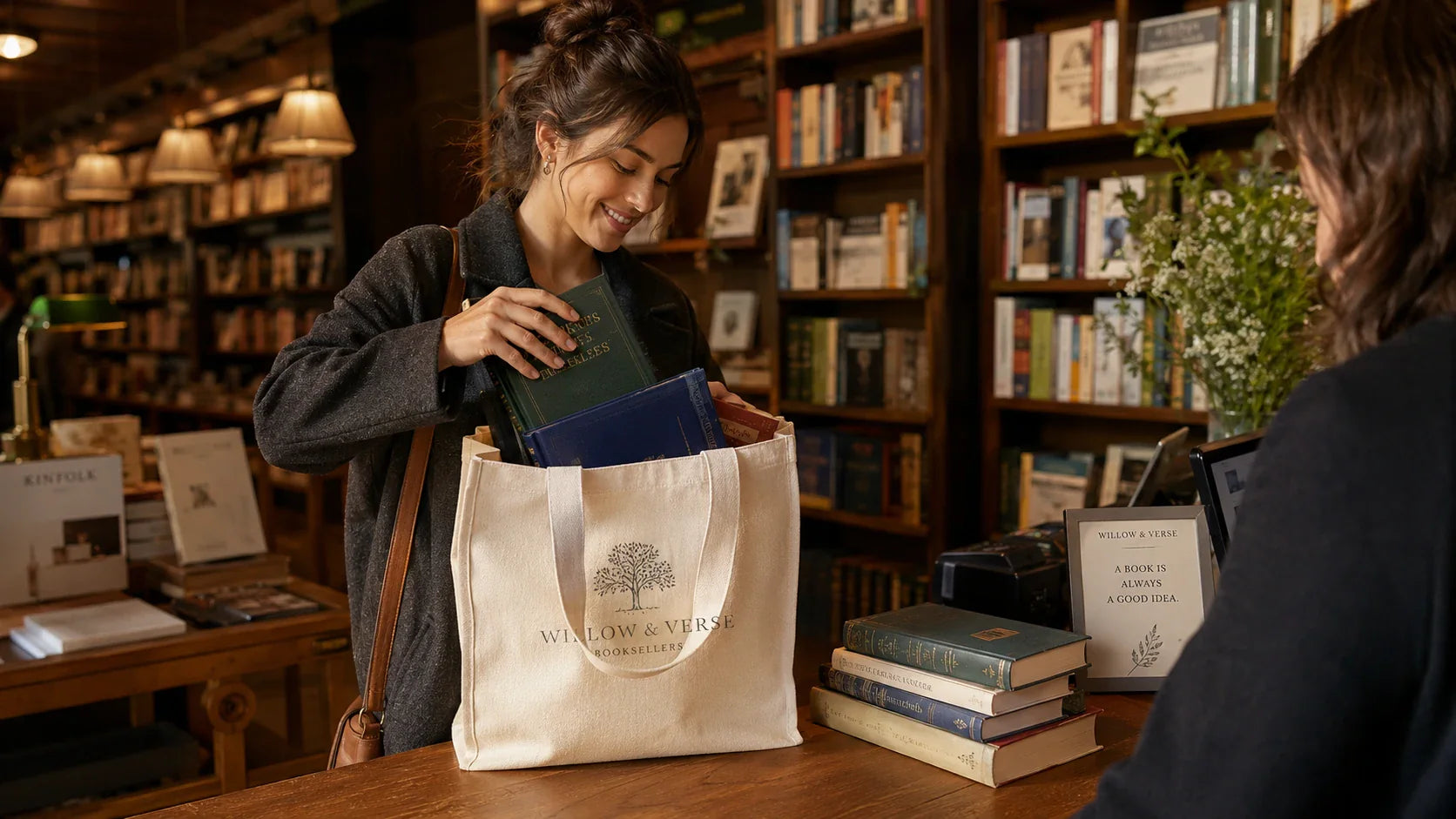 A customer packing heavy hardcover books into a branded custom canvas tote bag at a bookstore checkout.
