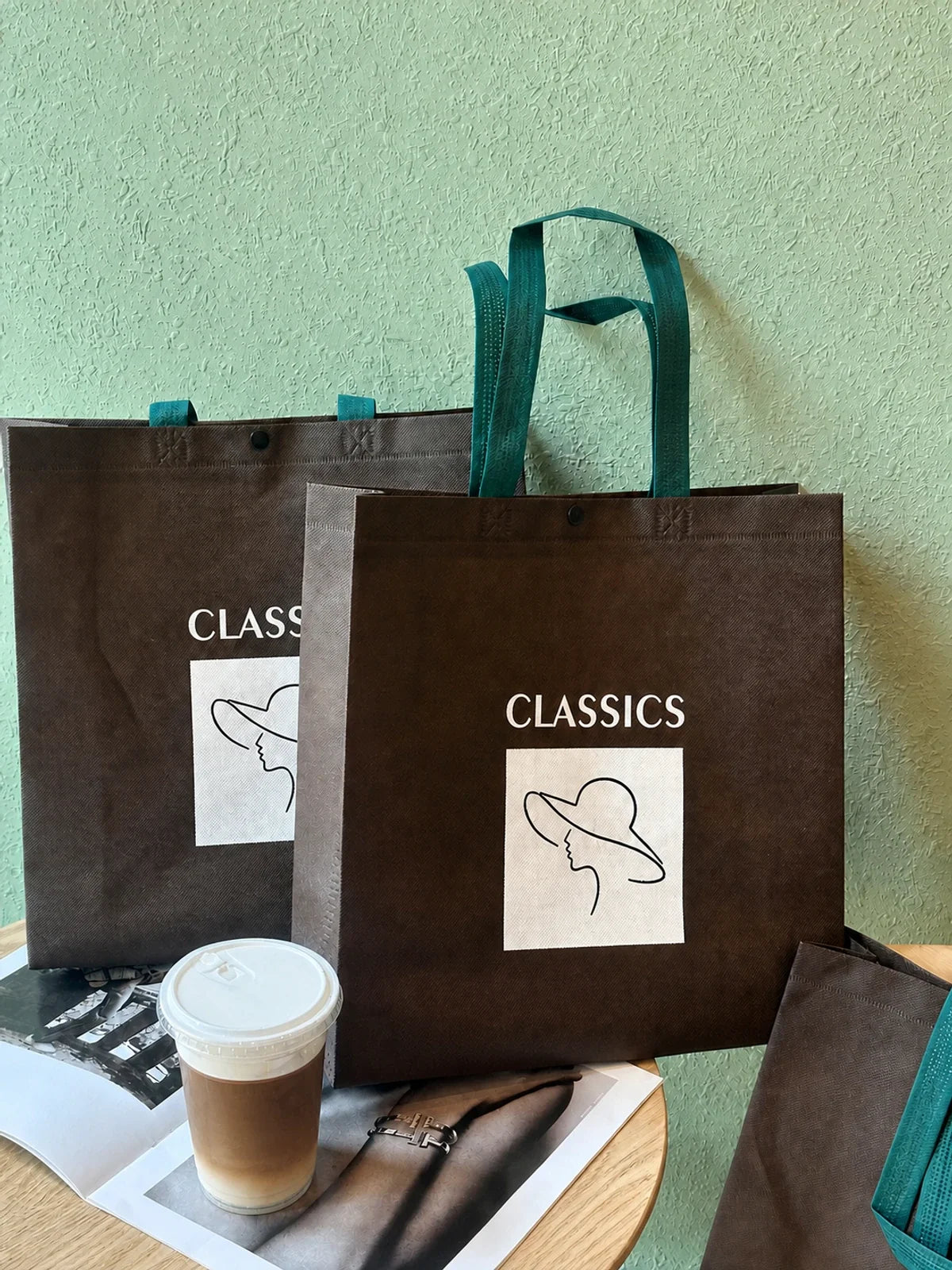 Two brown snap-closure non-woven shopping bags with green handles shown in different sizes