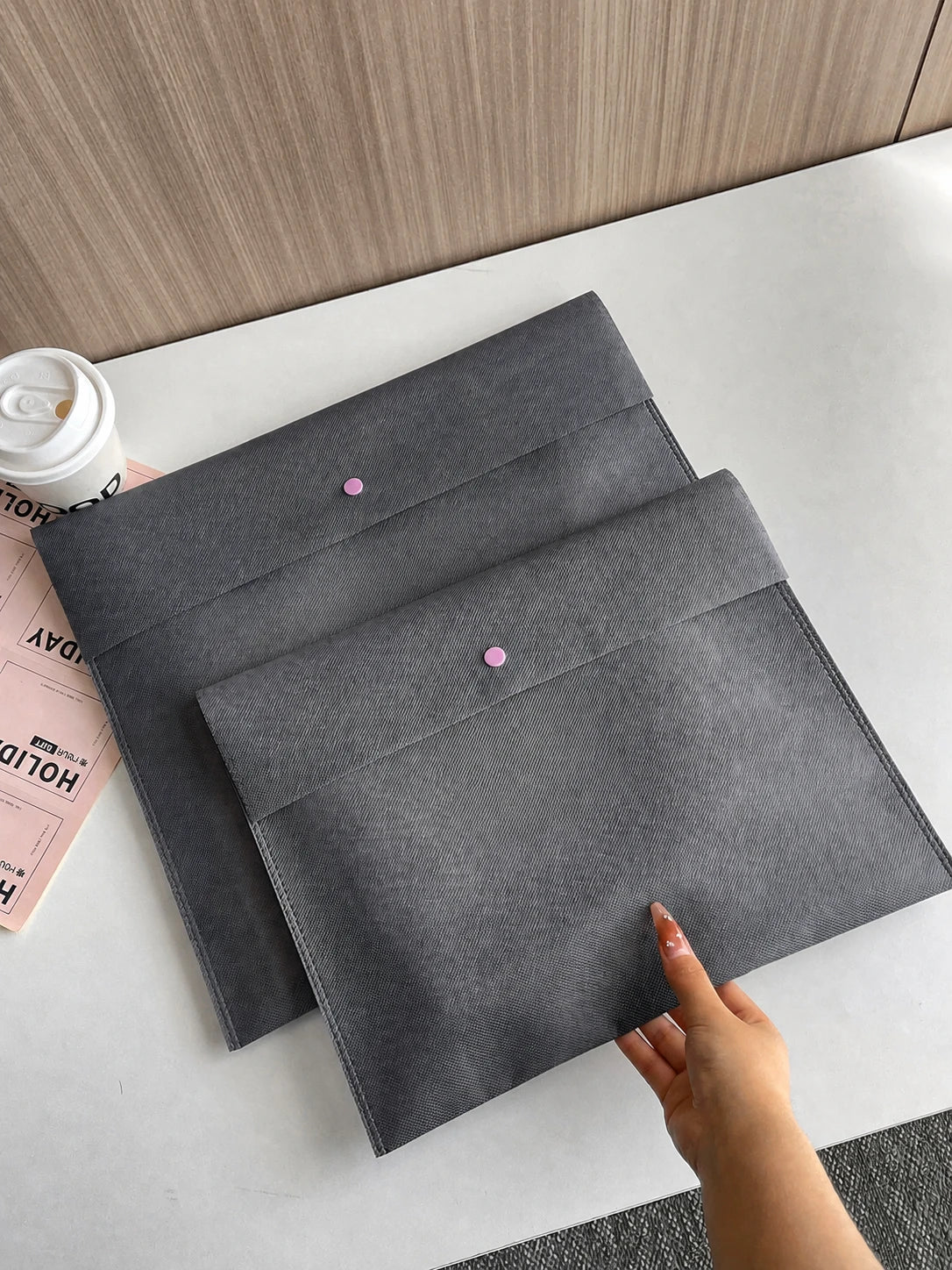 Gray envelope-style non-woven bags in three sizes on a tabletop