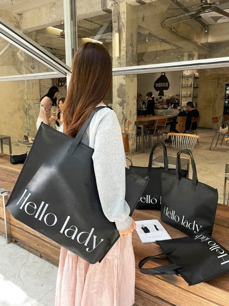 Woman carrying a large black zippered non-woven shopping bag