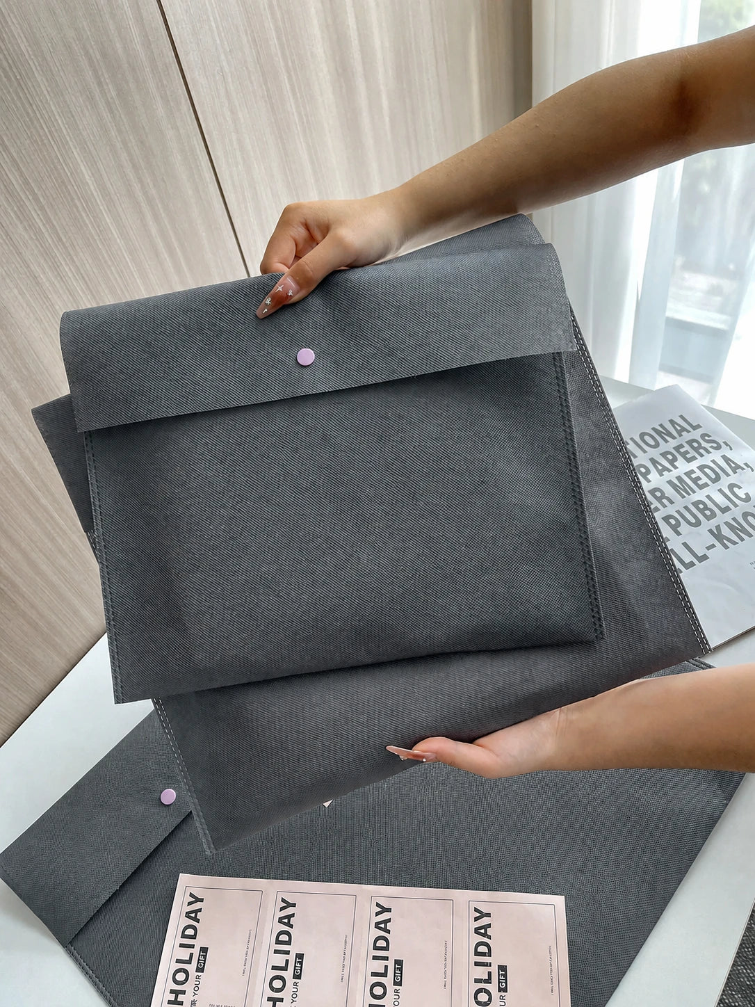 Person holding a gray envelope-style non-woven gift bag