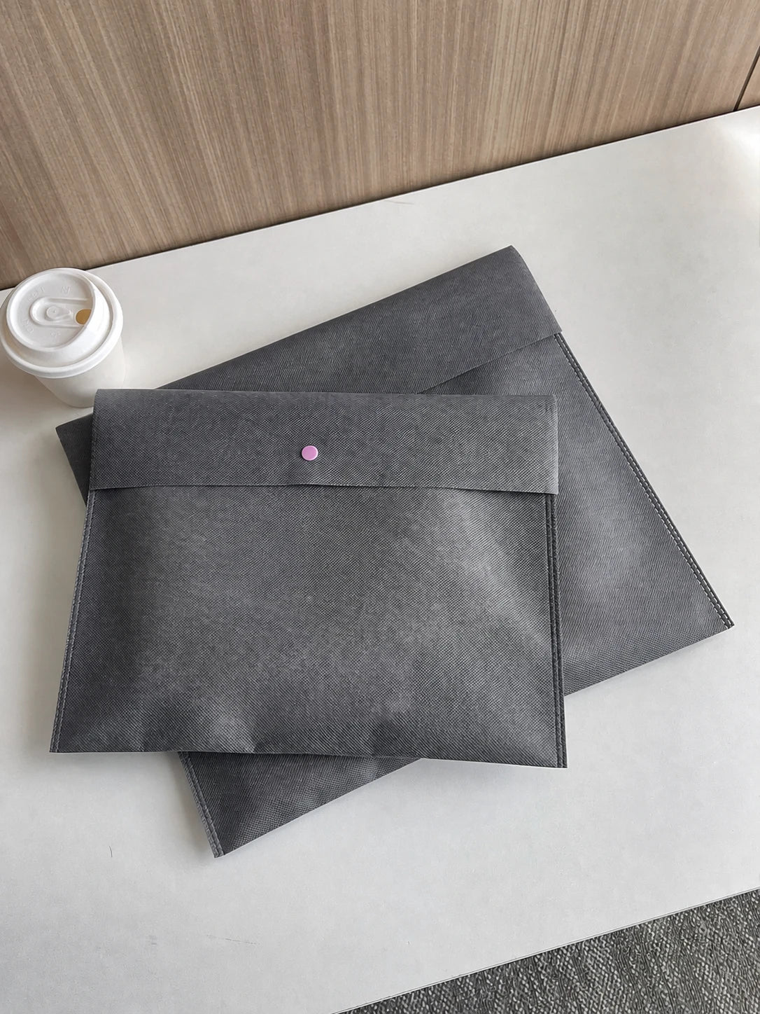 Gray snap-closure non-woven envelope bags shown in three sizes