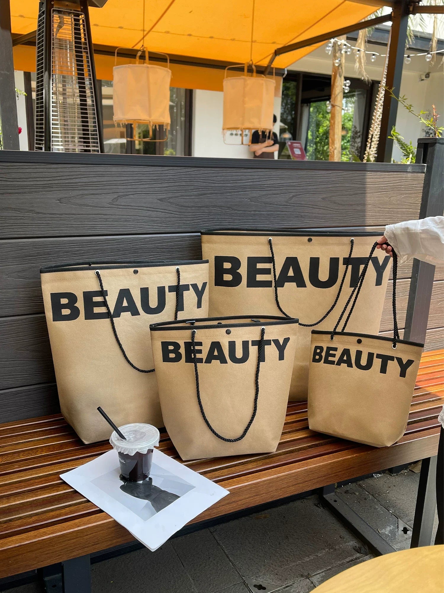 Brown trapezoid non-woven tote bags shown in multiple sizes