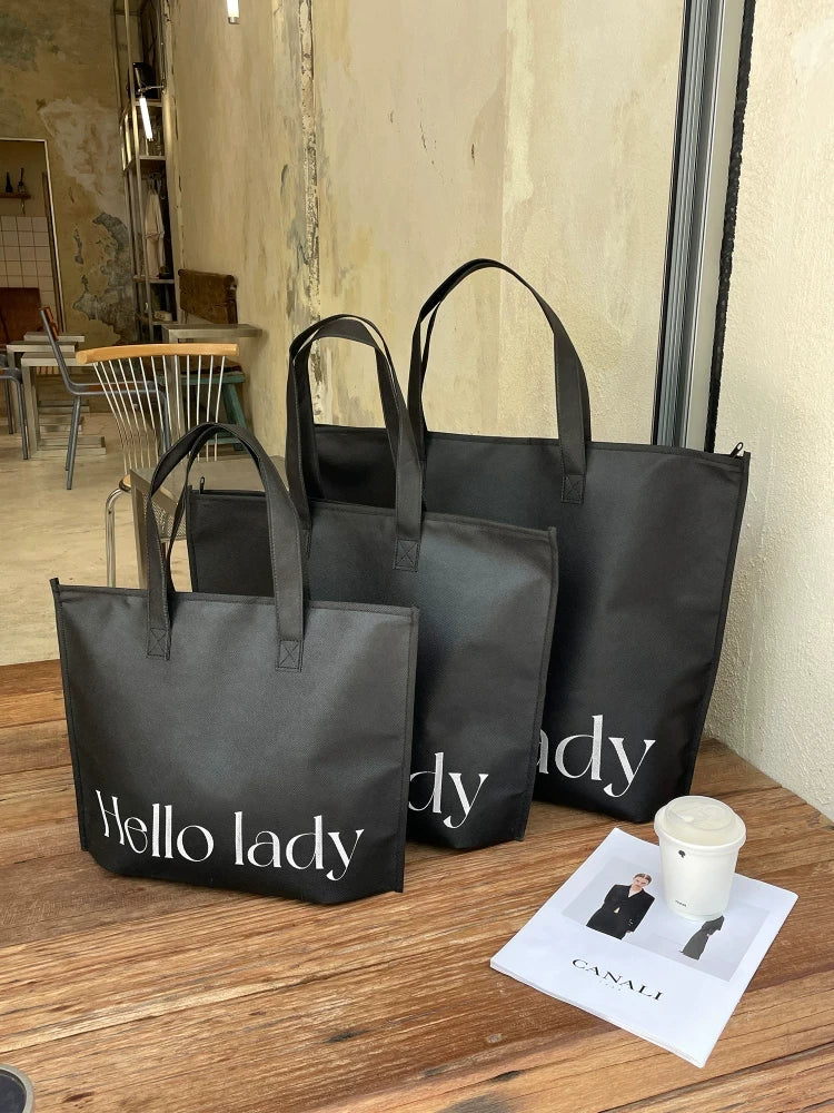 Black zippered non-woven tote bags shown in three sizes