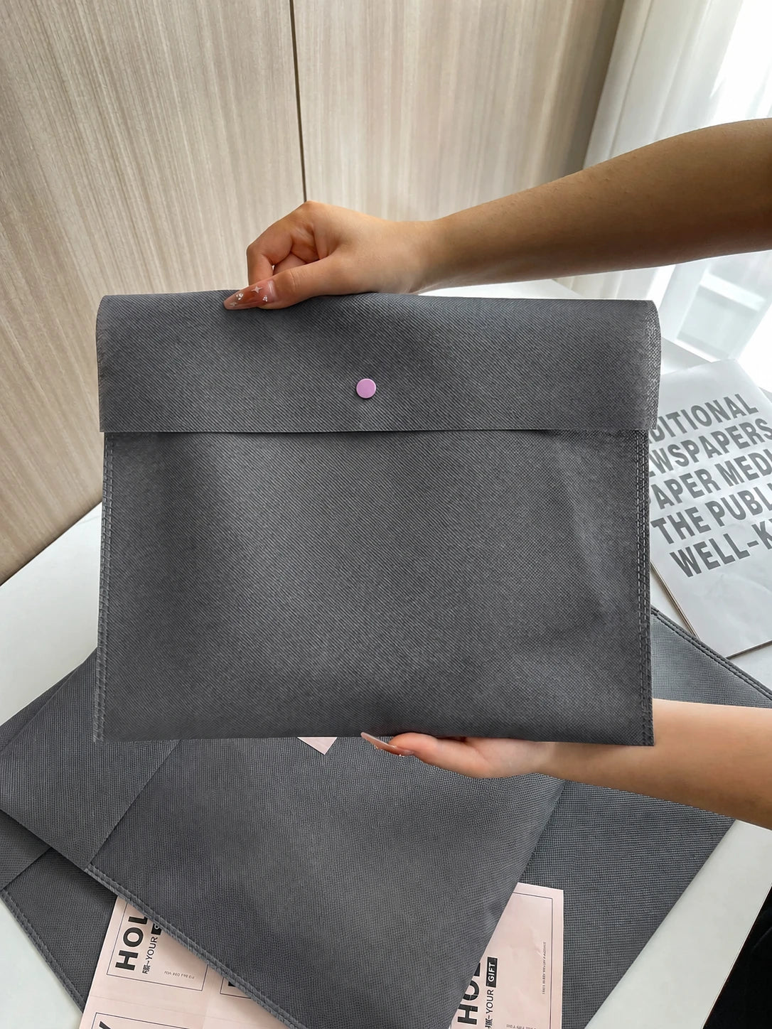 Close-up of a gray envelope-style non-woven bag with snap closure
