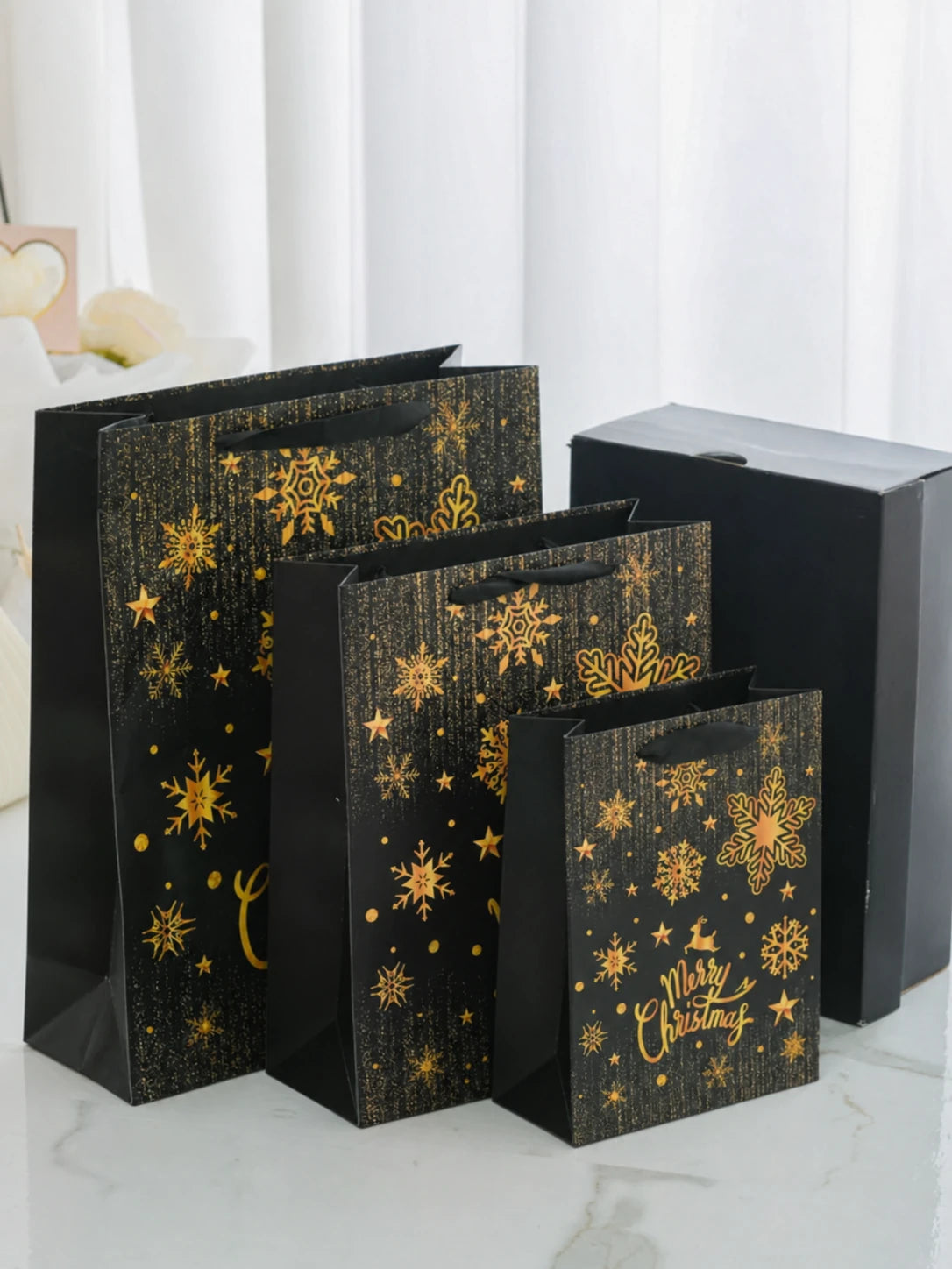 Black-and-gold Christmas paper gift bags shown in three sizes