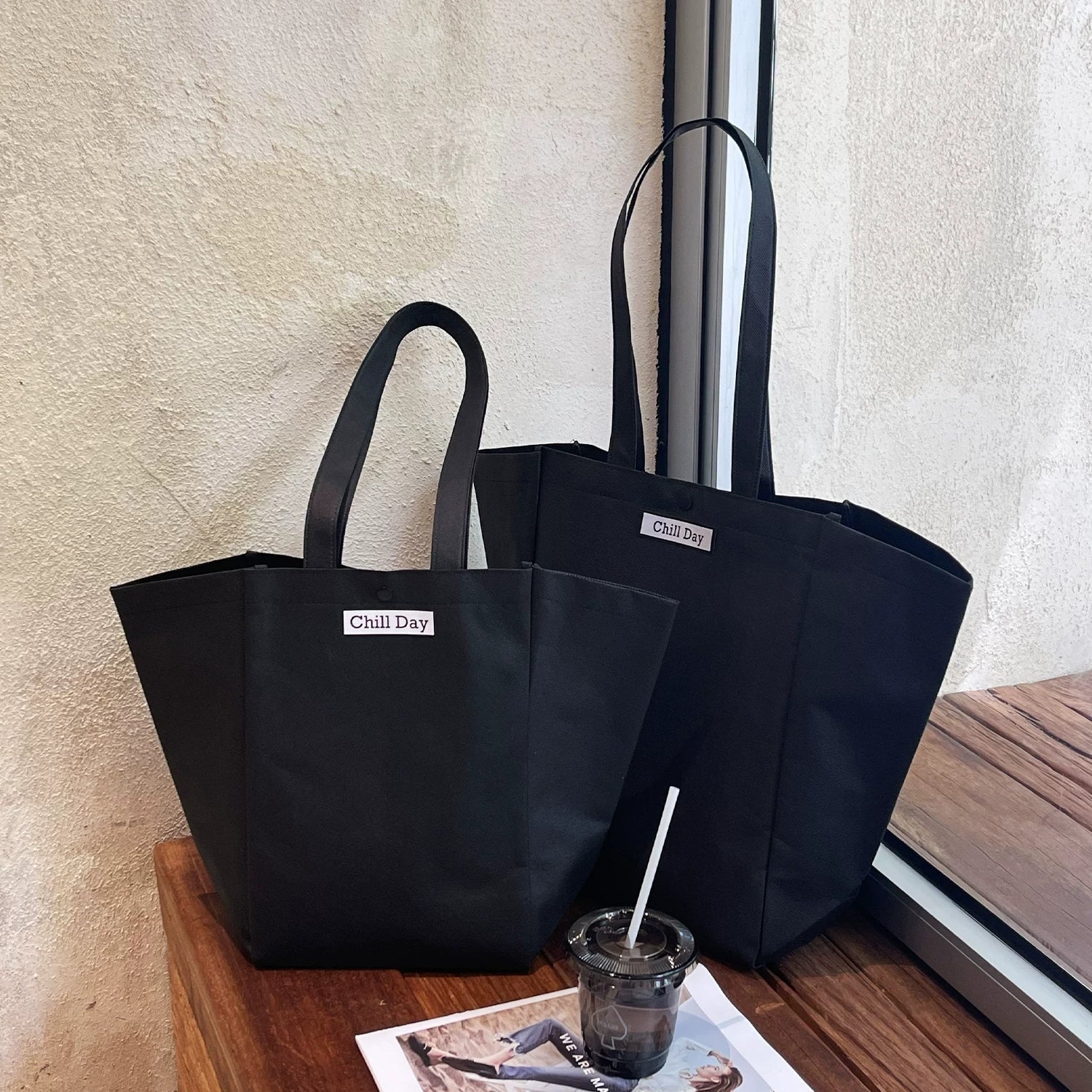 Black trapezoid non-woven tote bag with woven label