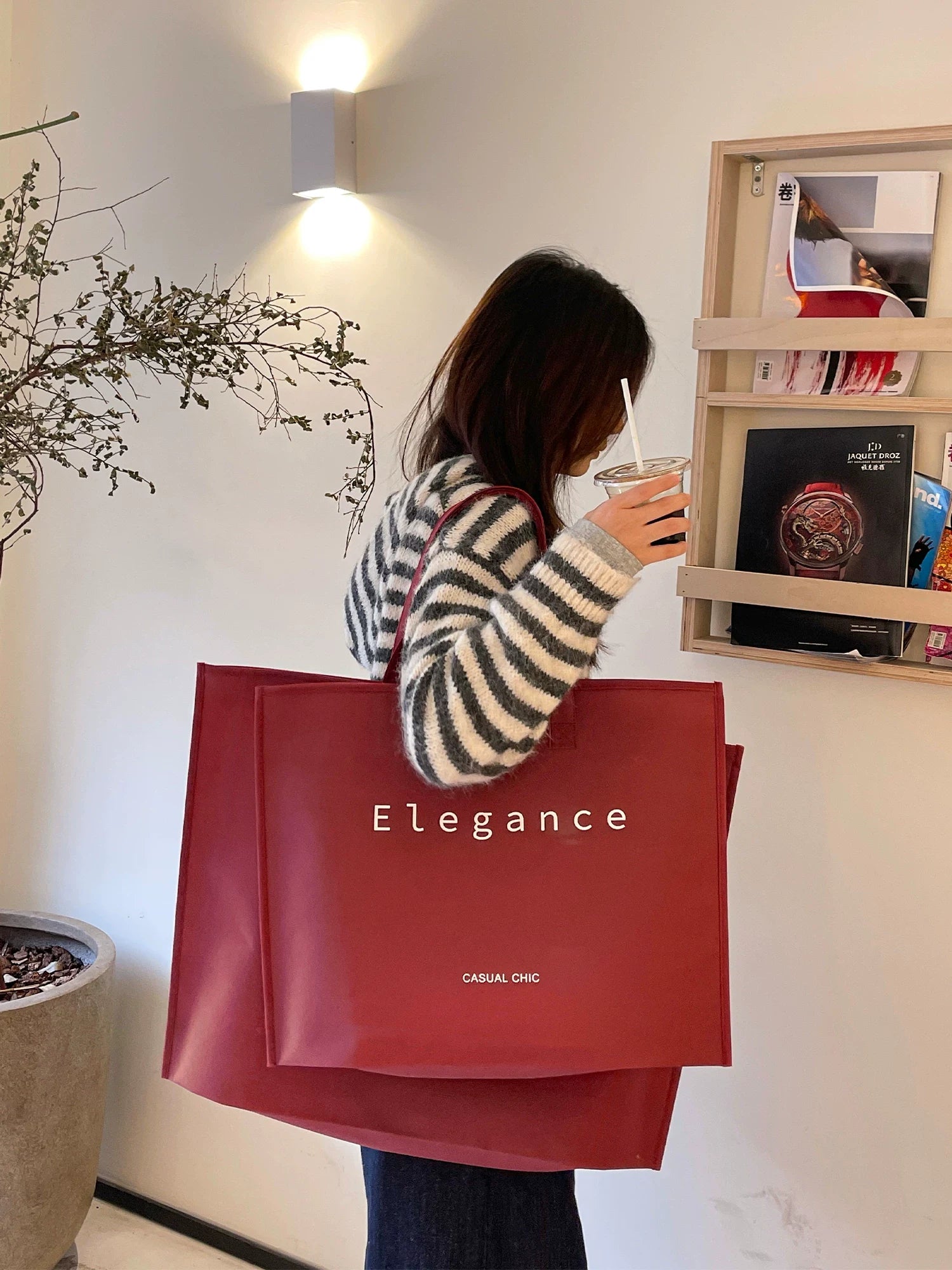 Burgundy zipper non-woven tote bag carried in a retail setting
