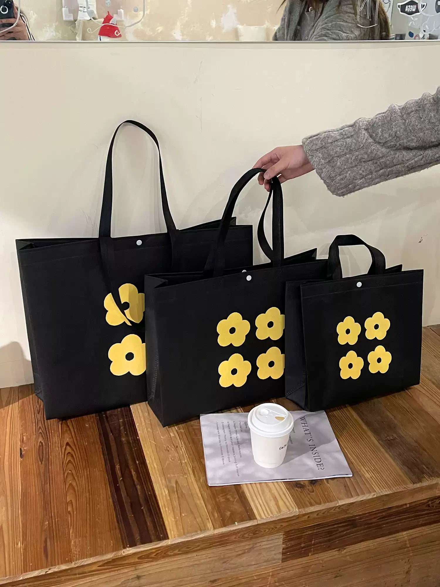 Yellow flower non-woven tote bags displayed in four available sizes