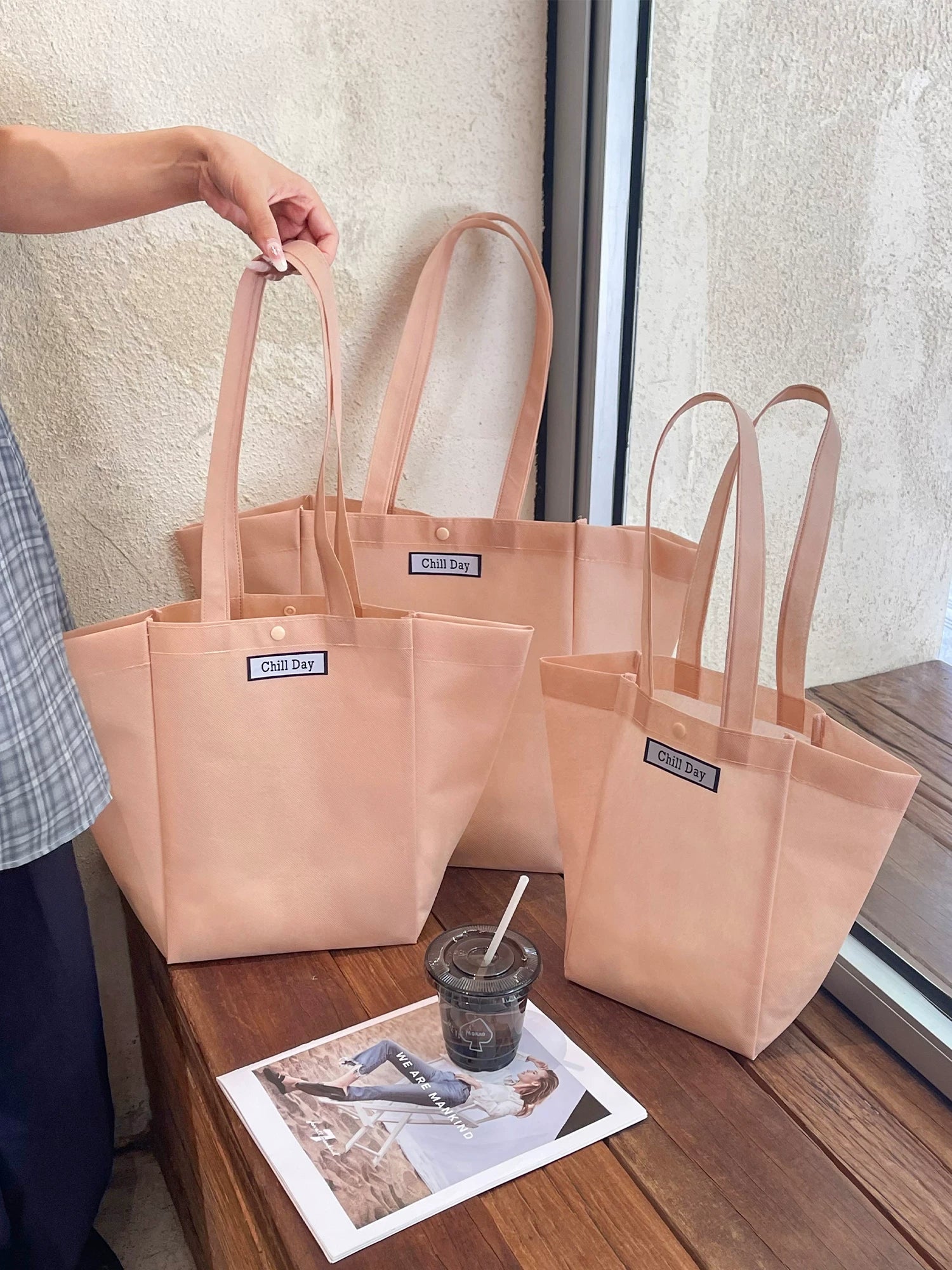 Custom trapezoid non-woven tote bags in light pink with woven labels