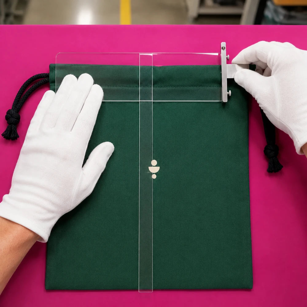 Inspector checking print alignment and seam accuracy on an emerald drawstring bag
