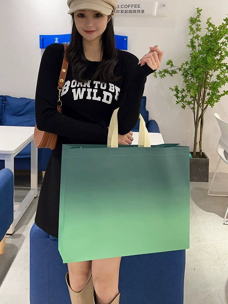 Model carrying a gradient green non-woven tote bag