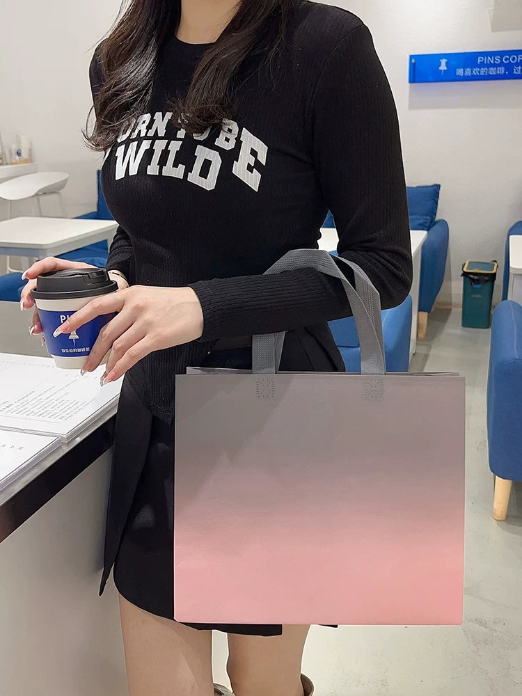 Model carrying a gradient pink non-woven tote bag
