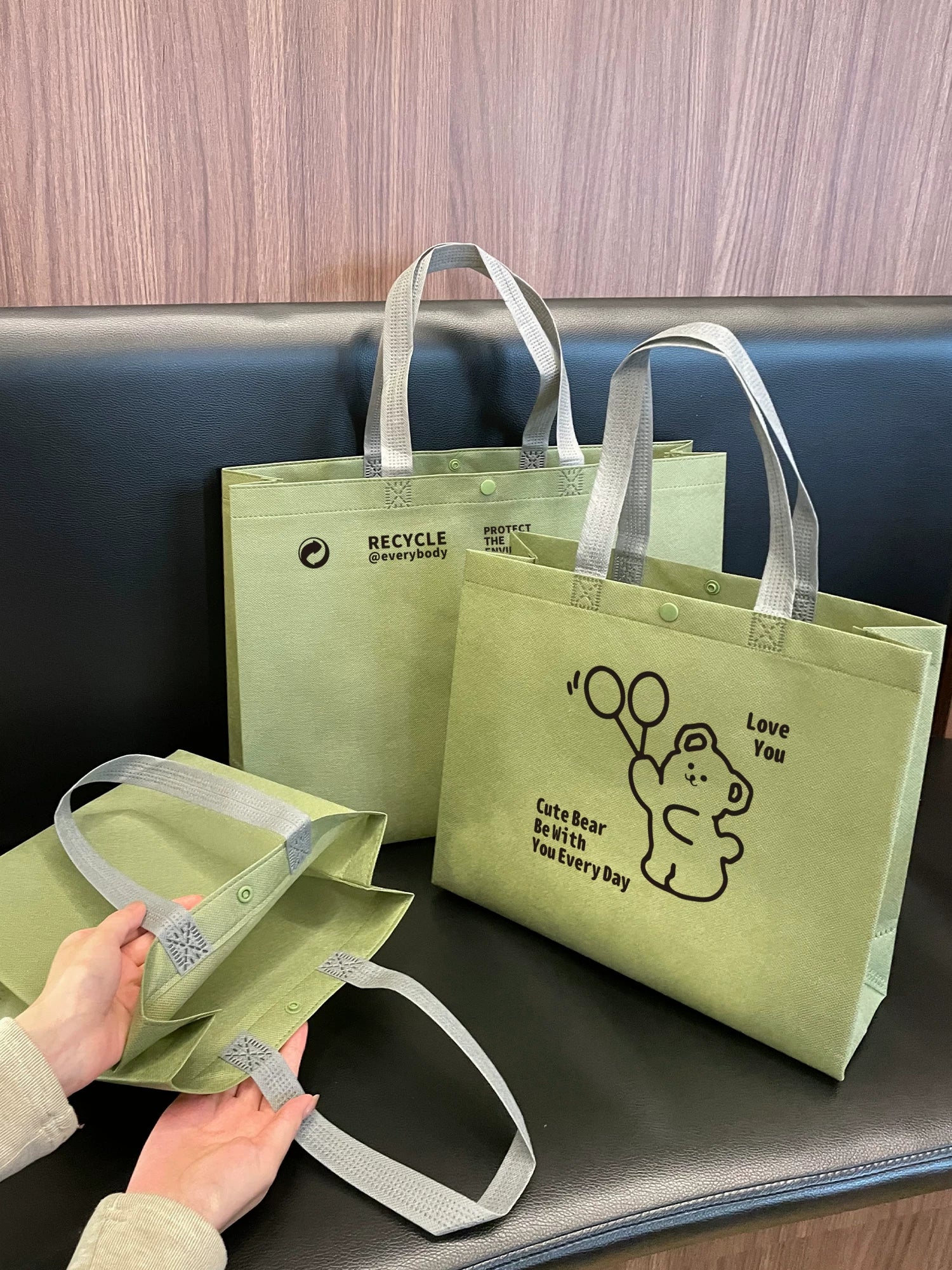 Green reusable non-woven snap closure tote bags in multiple sizes