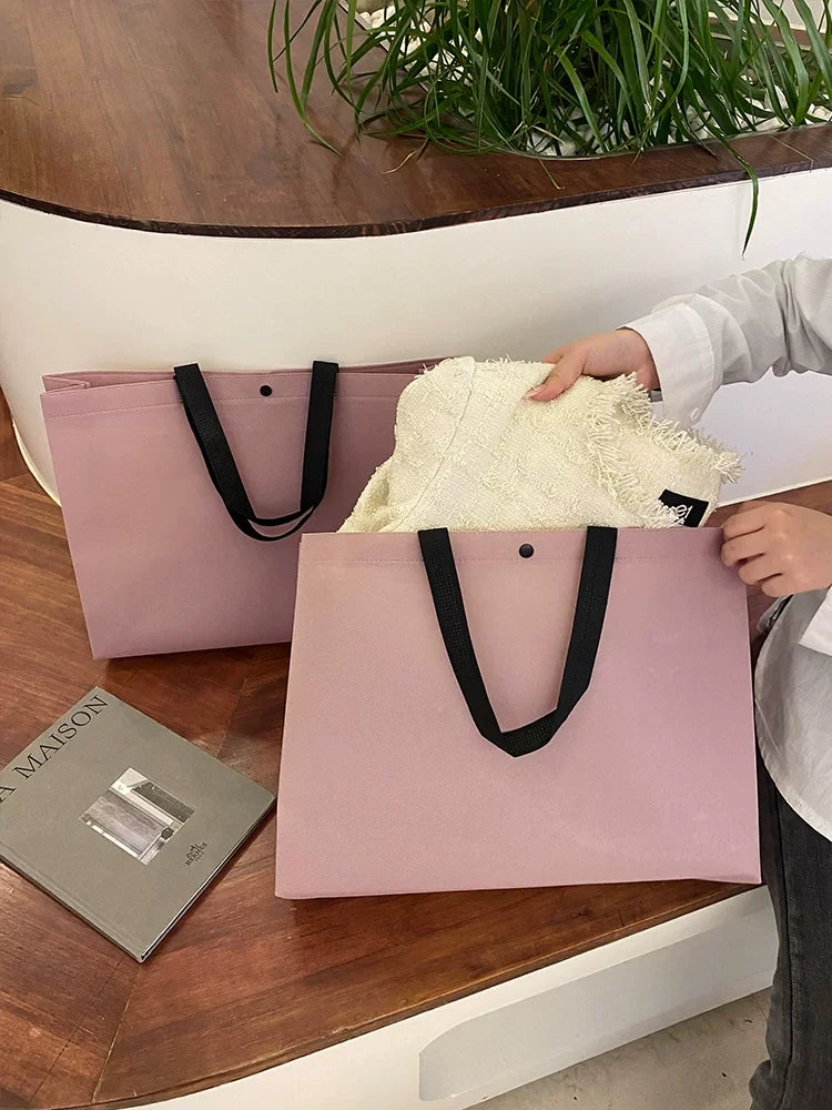 Purple non-woven tote bag holding folded apparel