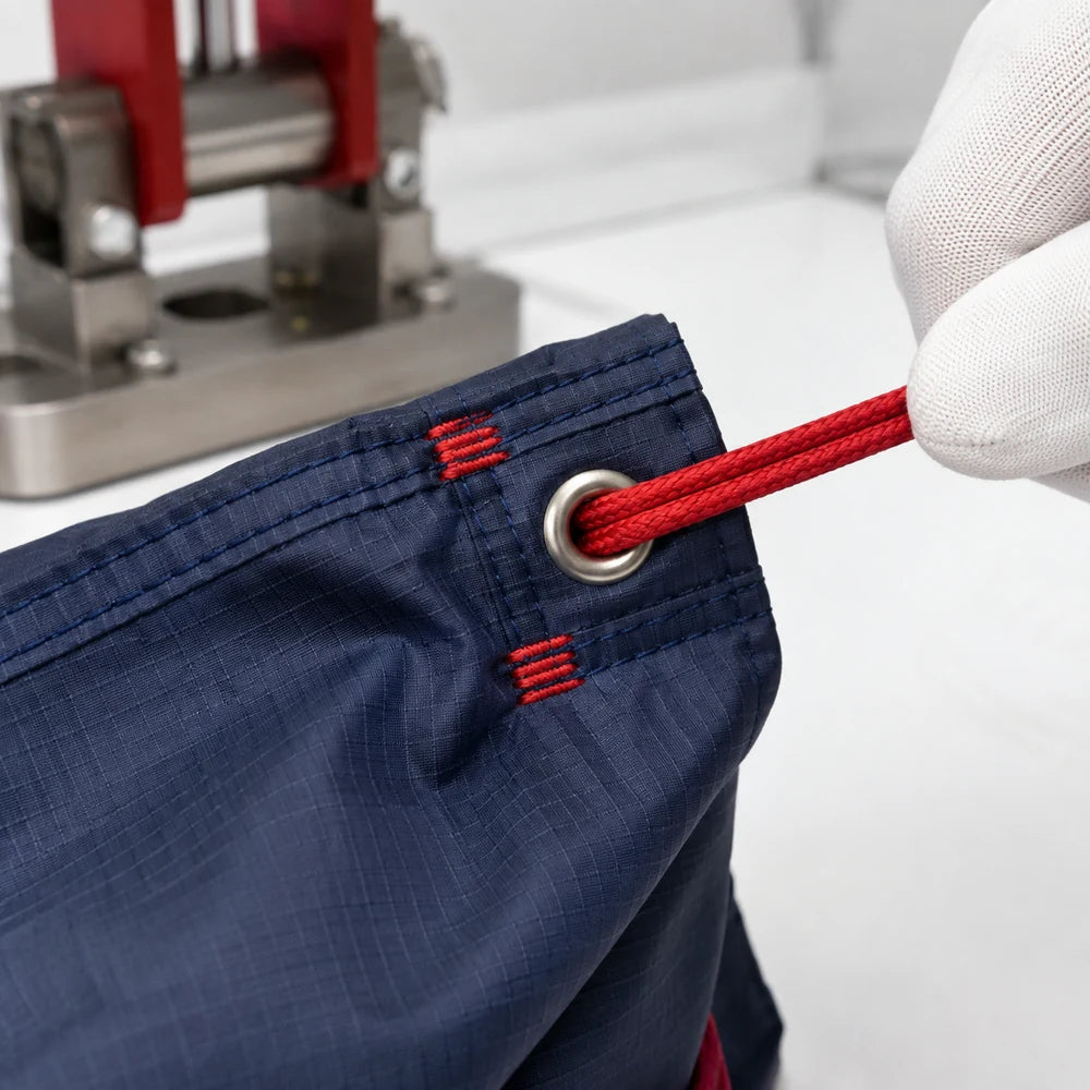 Red bar-tack reinforcement around a drawstring channel metal eyelet
