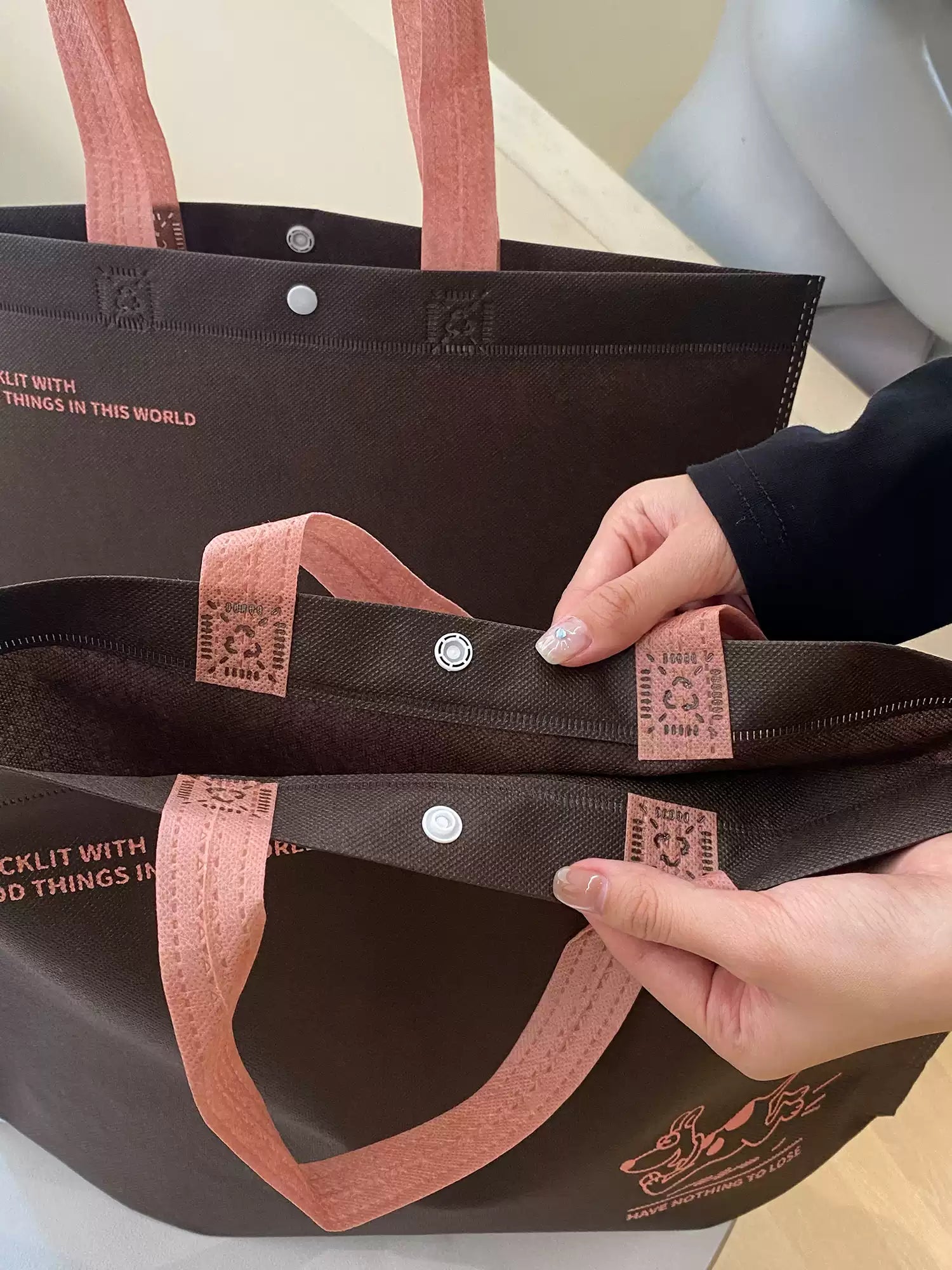 Reinforced handles and snap closure detail on non-woven tote bag