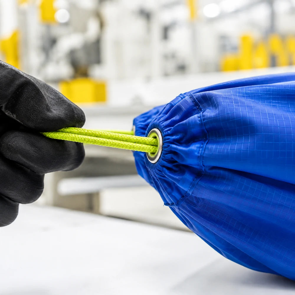Cobalt ripstop channel with lime cord gliding through a metal eyelet