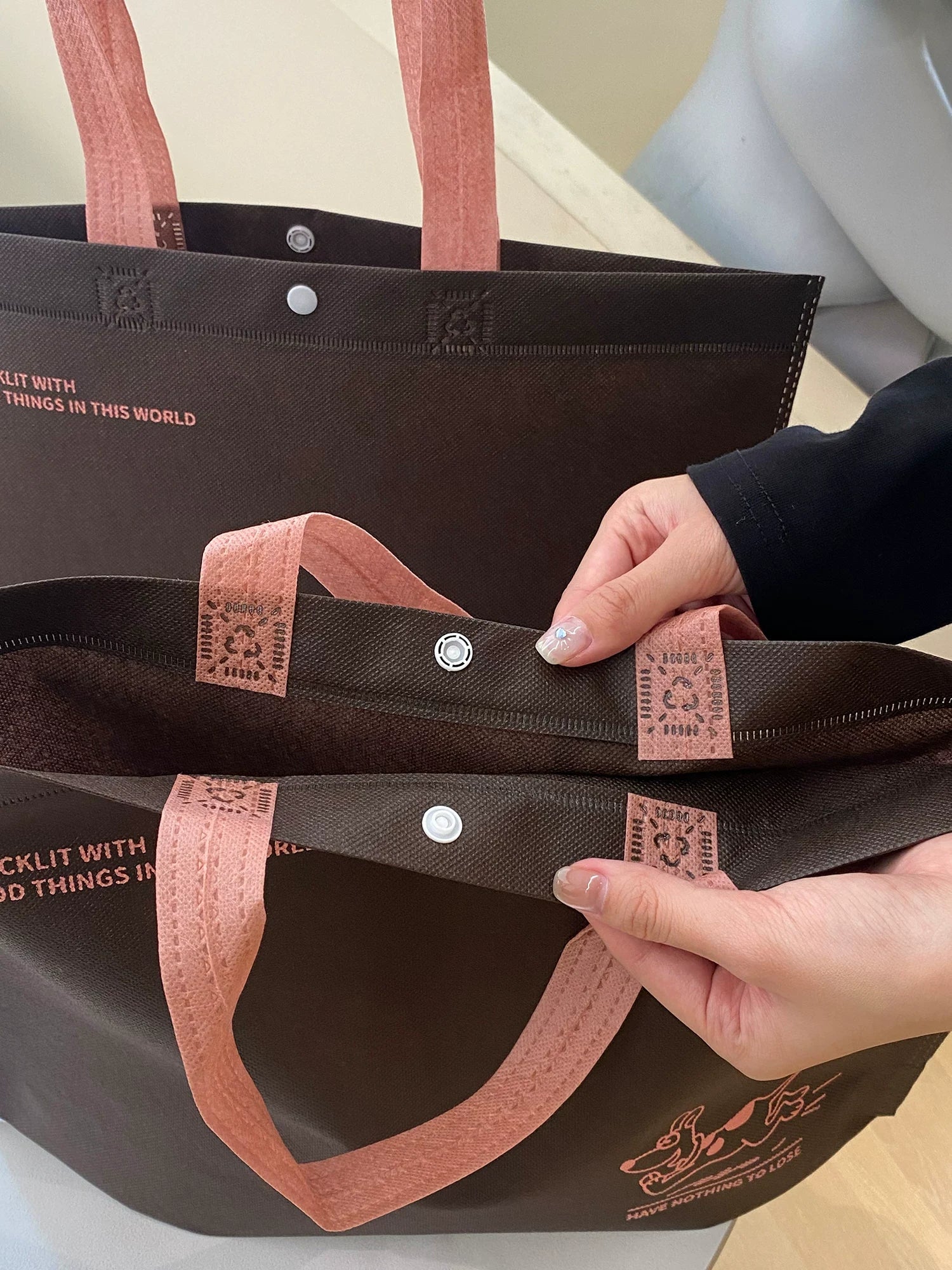 Snap button and reinforced handle details on a brown non-woven tote bag